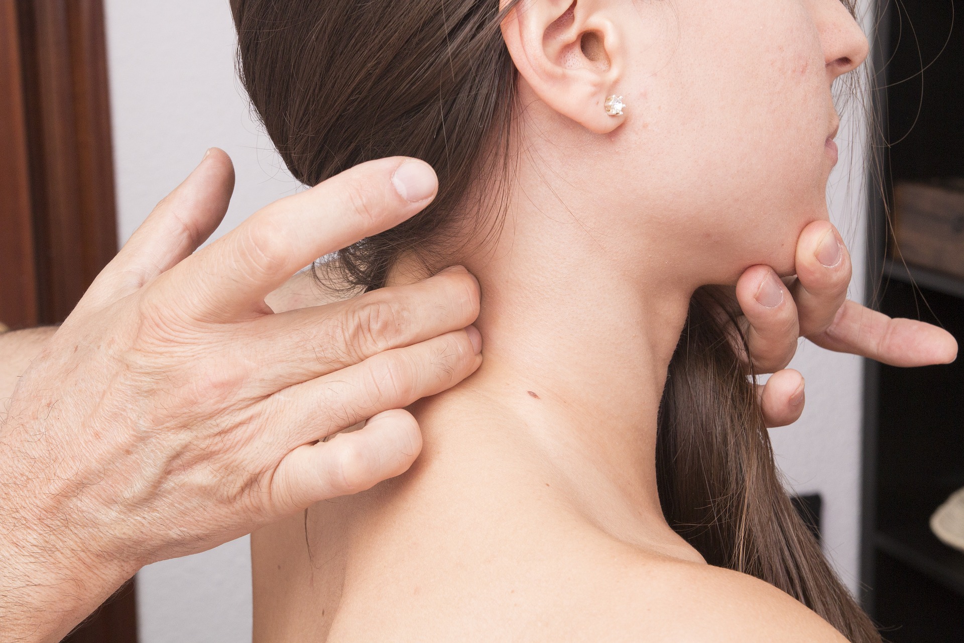 Doctor providing trigger point therapy and myofascial release techniques on the neck of a young woman